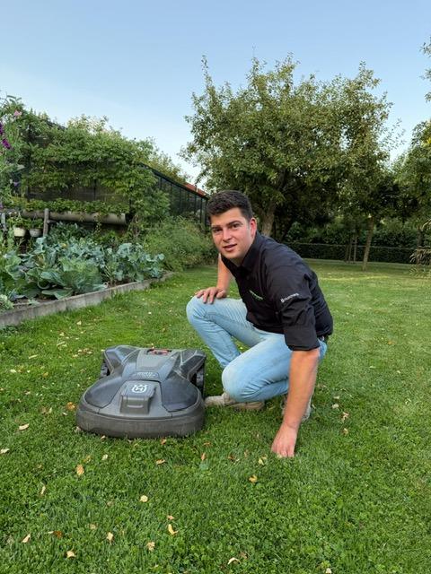 Eén van de broers van Groenekamp bij een Automower-robotmaaier in de tuin.